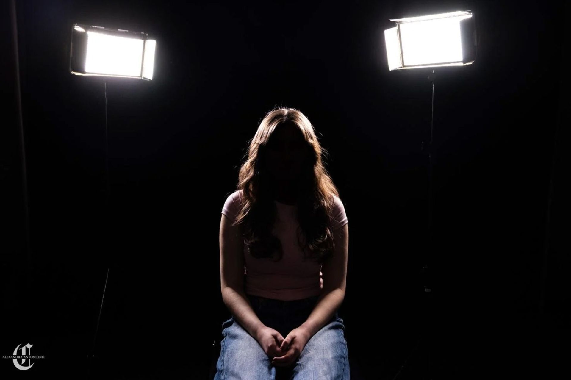 Female student in shadows posing as to hide her identity