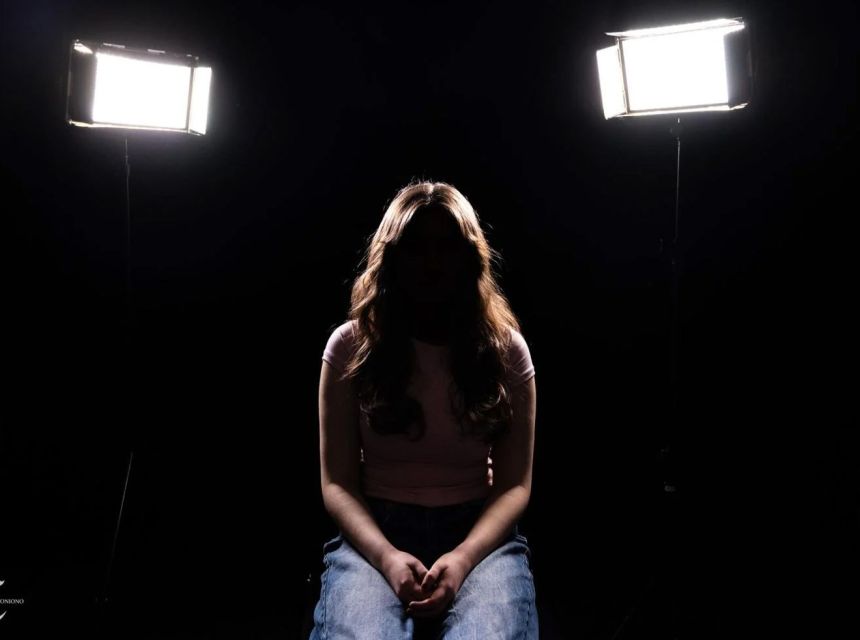 Female student in shadows posing as to hide her identity