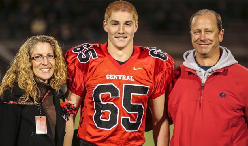 Tim Piazza, in a football uniform, stands between his mother and father for a senior night photo